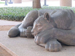 Bronze sculpture of a resting panther on a stone base.