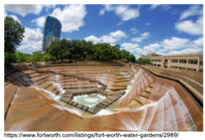 Multilevel urban water garden with cascading steps under a partly cloudy sky.